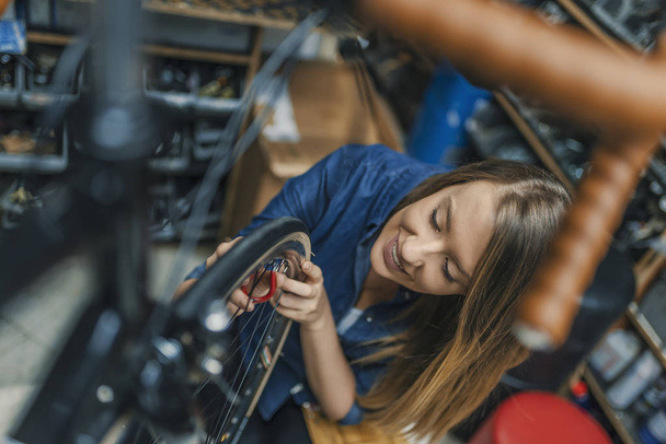 Young woman repairing bicycle. Woman working at workshop. Small business owner. Bike maintenance. Repair technician bicycles was repaired gear bike shop. - Foto, Imagem