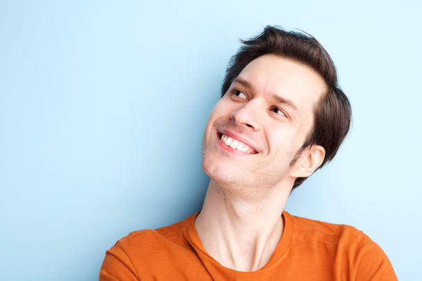 Close up portrait of happy young man smiling against blue background - Photo, Image