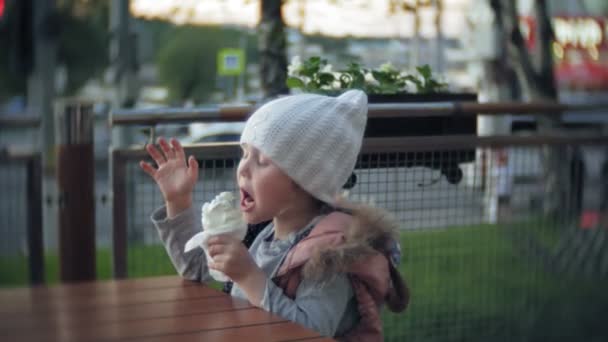niedliches Kleinkind Mädchen mit weißer Strickmütze Eis essen - Filmmaterial, Video