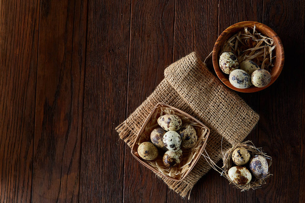 Rustic still life with quail eggs in bucket, box and bowl on a linen napkin over wooden background, selective focus - Foto, Bild