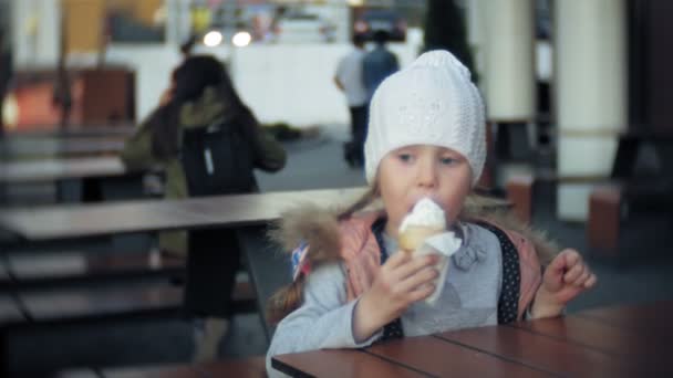 niedliches Kleinkind Mädchen mit weißer Strickmütze Eis essen - Filmmaterial, Video