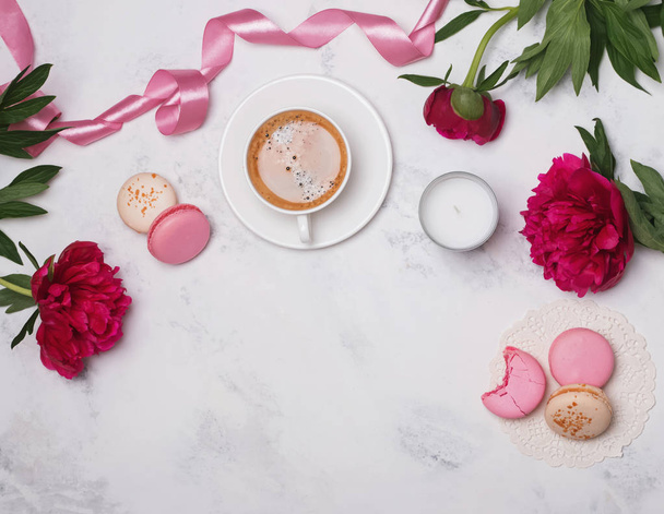 Coffee, pink peonies and macarons on the marble table - Photo, image