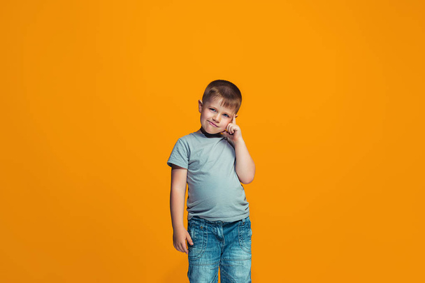 The happy teen boy standing and smiling against orange background. - Φωτογραφία, εικόνα
