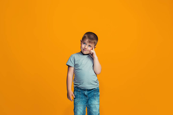The happy teen boy standing and smiling against orange background. - Foto, imagen