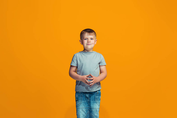 The happy teen boy standing and smiling against orange background. - Photo, image