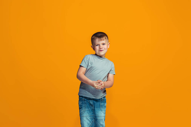 The happy teen boy standing and smiling against orange background. - Foto, afbeelding