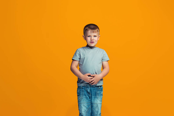 The happy teen boy standing and smiling against orange background. - Zdjęcie, obraz