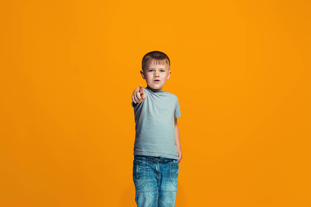 The happy teen boy pointing to you, half length closeup portrait on orange background. - Zdjęcie, obraz