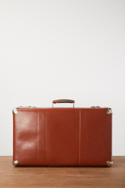 Closed leather suitcase on wooden background - Фото, изображение