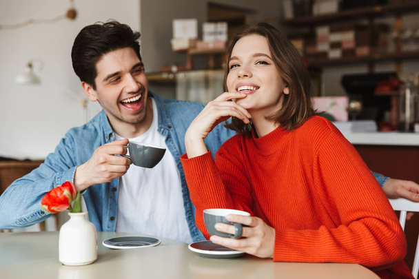 Happy couple woman and man smiling and having leisure in cafe while drinking coffee or tea in morning - Zdjęcie, obraz