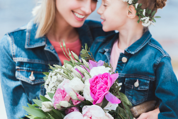 selective focus of mother and daughter in wreath with peony bouquet  - Foto, imagen