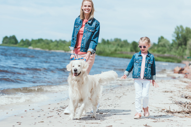 happy family walking with golden retriever dog on sea shore - Foto, Imagem