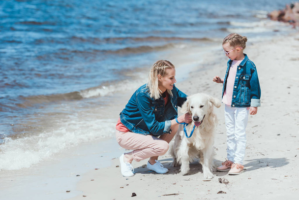 mother and kid walking with golden retriever dog on sea shore - Photo, image