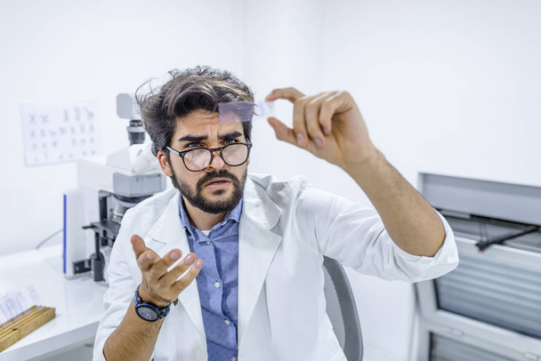 Concenrated scientist working with microscope in laboratory. Science Laboratory. Man scientist in white coat looking at glass microscope slide in lab - Fotografie, Obrázek
