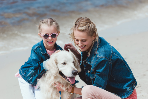 smiling family with golden retriever dog on sea shore - Fotografie, Obrázek