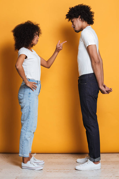 Full length portrait of an angry afro american couple having an argument isolated over yellow background - Foto, immagini