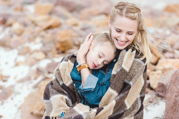sonriente madre abrazando a su adorable hija dormida en manta
 - Foto, imagen