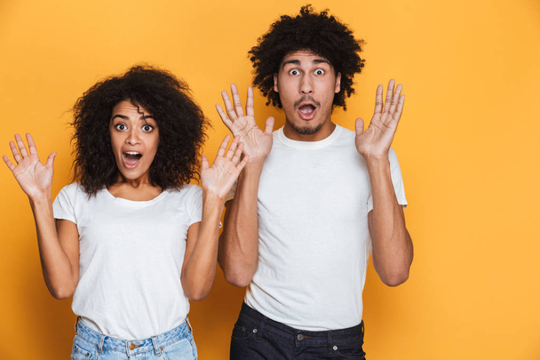 Portrait of a shocked young afro american couple screaming isolated over yellow background - Fotoğraf, Görsel