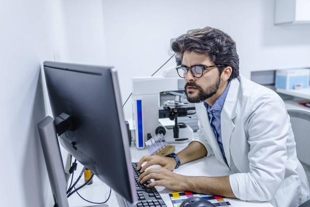 Friendly male doctor is sitting at the table and working in the hospital office. Ready to examine and help patients. High level and quality medical service concept. - Photo, image
