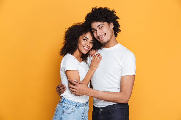 Portrait of a lovely young afro american couple hugging isolated over yellow background - Valokuva, kuva