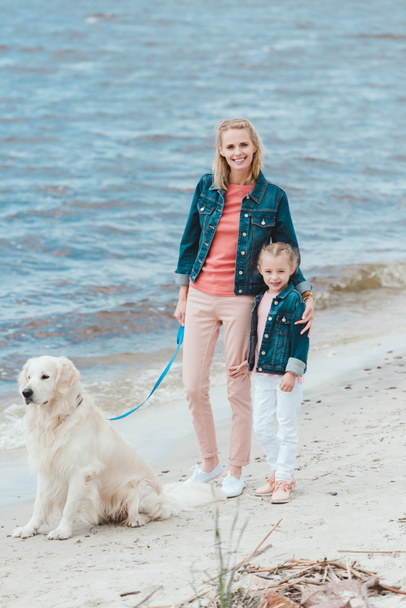 beautiful family walking with golden retriever dog near the sea   - Zdjęcie, obraz