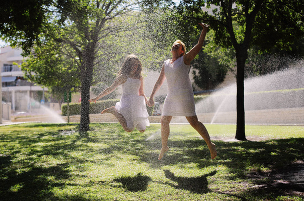 Matka i córka zabawy pod krople wody w parku - Zdjęcie, obraz