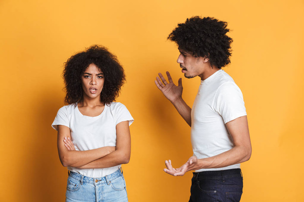 Portrait of an angry afro american couple having an argument isolated over yellow background - Photo, Image