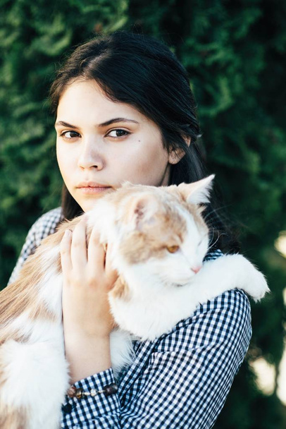 Χαριτωμένο κορίτσι επισημασμένη γάτα κρατά στην αγκαλιά της - Φωτογραφία, εικόνα
