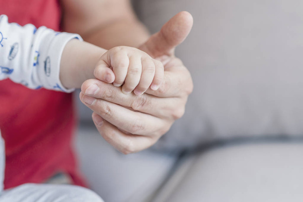 Father's hand holding kids hand. Concept love of family. Baby hand holding by adult. The father is holding the hand of the baby. Father's and baby's hands. Family concept  - Fotó, kép