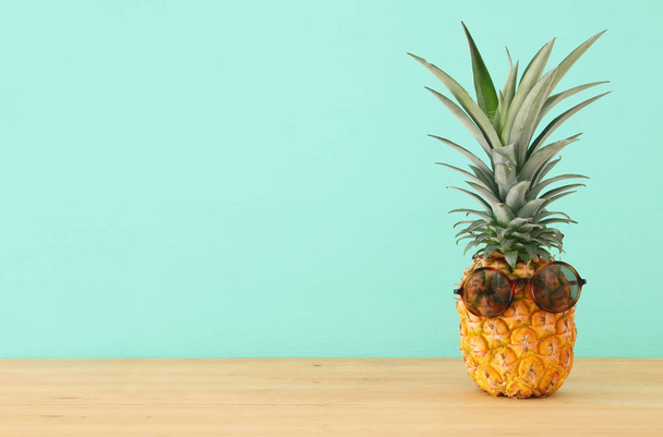 Pineapple on wooden table with funny sunglasses. Beach and tropical theme. - Zdjęcie, obraz
