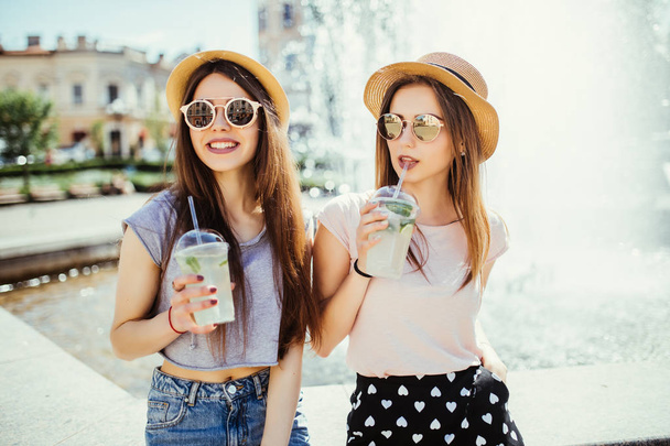 カクテルを飲んで夏の日当たりの良い都市で 2 つの美しい若い女の子 - 写真・画像