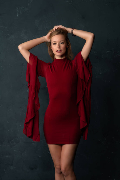 Tall slender blonde in a short red dress with voluminous sleeves - Фото, изображение