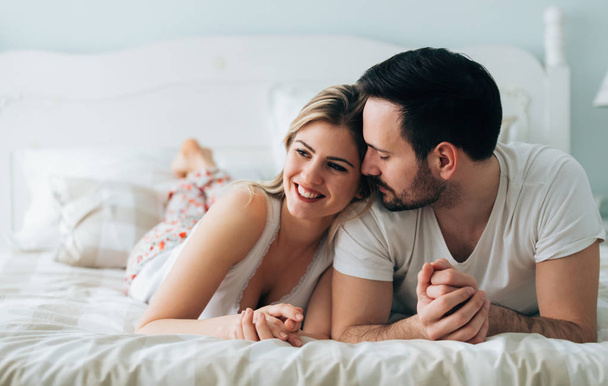 Portrait of young attractive loving couple in bedroom - Фото, зображення