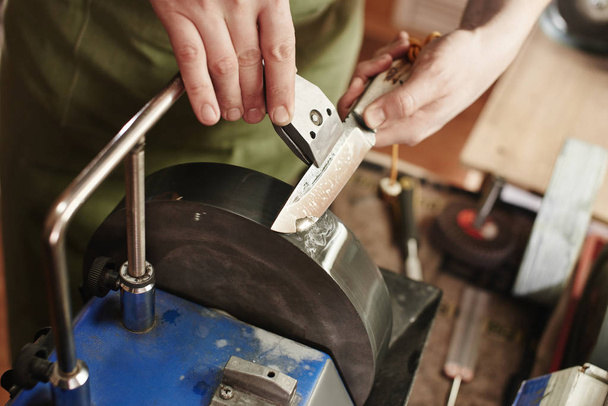 close up view of male hands sharpening the knife at workshop - Foto, Bild