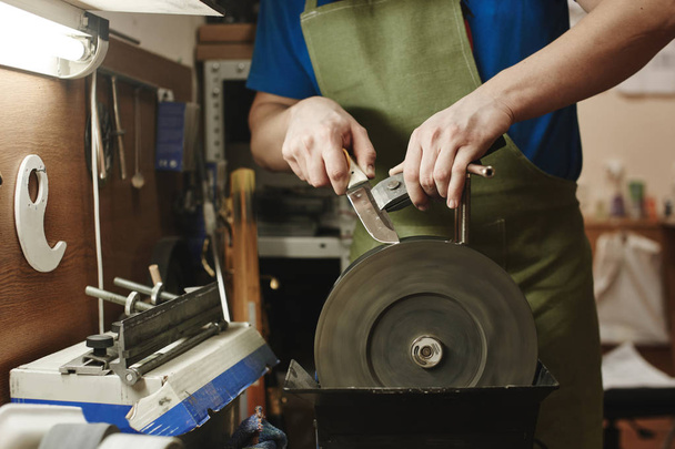 master sharpening blade on machine, close-up, making of knife concept  - Fotó, kép