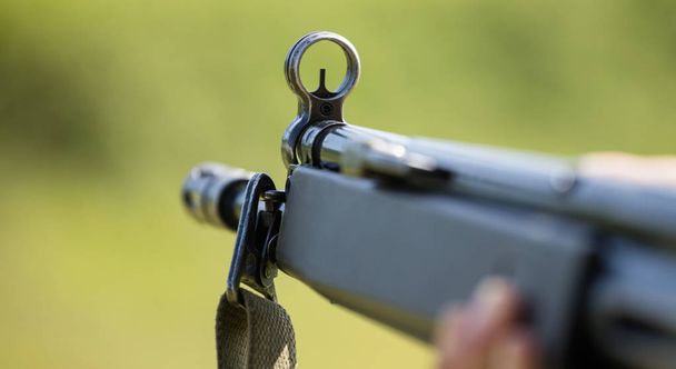 Vuurwapen handgun in man' s hand die het doel markeert. Voorzijde van wapen met close-up op de achtergrond wazig natuur. - Foto, afbeelding