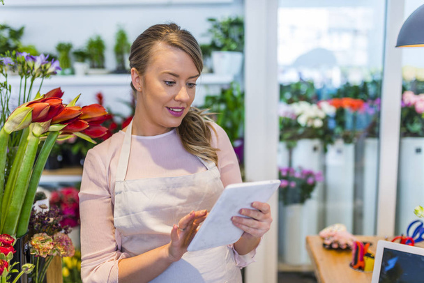 people, business, technology, sale and floristry and concept - happy smiling florist woman with tablet pc computer at flower shop - Fotografie, Obrázek