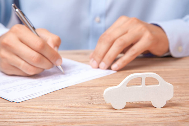 Araba Kiralama, kredi veya sigorta kavramı. Tişörtlü adam araba zemin karşı sözleşme imzalar - Fotoğraf, Görsel