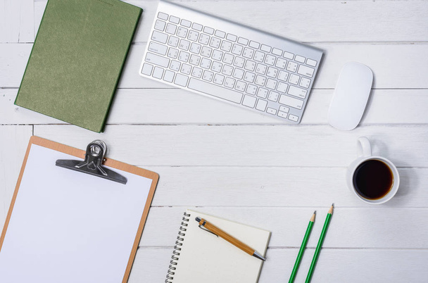 Dřevěný bílý úřadu stůl stůl s šálkem kávy, Notebook, pera, počítačové klávesnice myši na něm. Pohled shora s kopií prostor - Fotografie, Obrázek