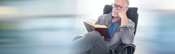 Portrait of mature man reading a book at home - Фото, изображение