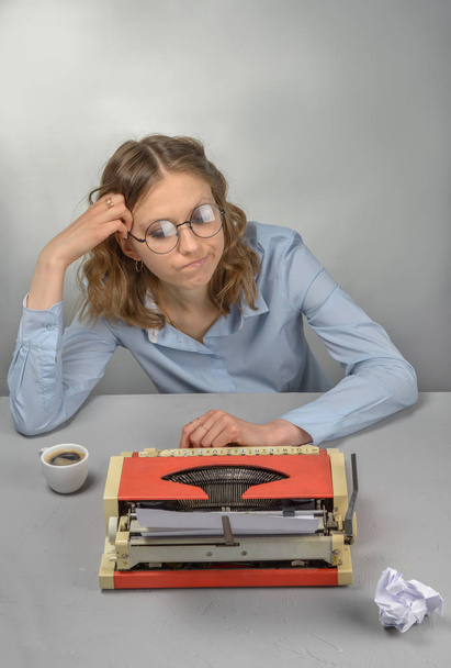 Mädchen - Schriftstellerin, rote Vintage-Schreibmaschine und eine Tasse Kaffee auf dem Tisch - Foto, Bild