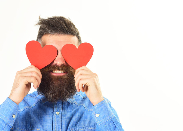 Man with beard holds red paper hearts like eyeglasses. - Fotó, kép