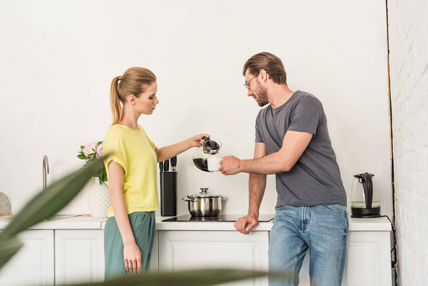 puolella näkymä nainen kaatamalla kahvia poikaystävä keittiössä
  - Valokuva, kuva