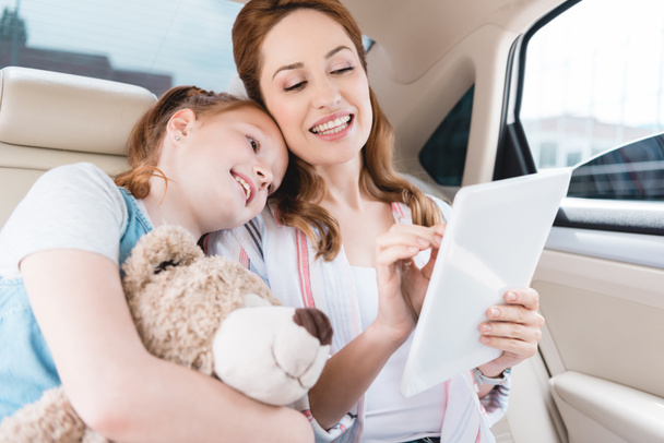 portrait of smiling family using digital tablet together in car - Photo, Image