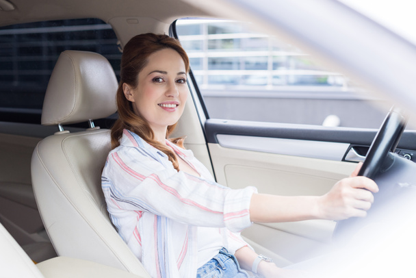 vue latérale de la femme souriante regardant la caméra tout en conduisant la voiture
 - Photo, image