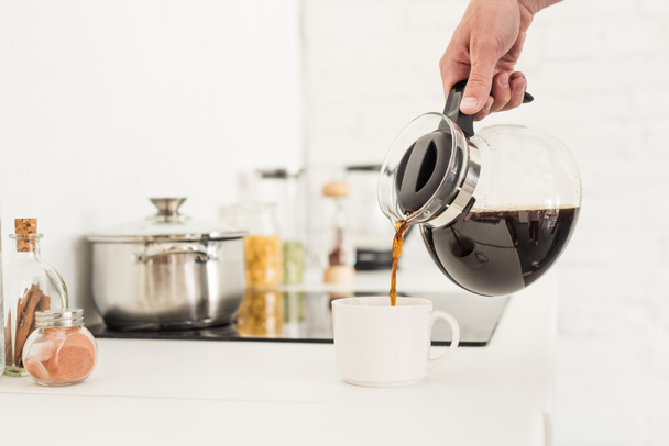 rajattu kuva mies kaatamalla kahvia kuppiin kahvinkeitin keittiössä
   - Valokuva, kuva