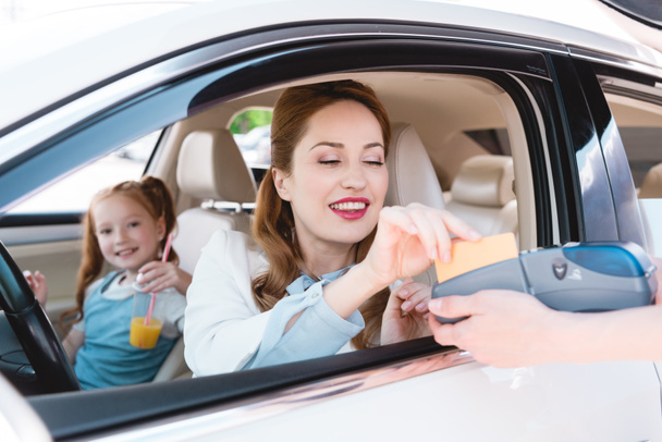 smiling businesswoman paying with credit card for take away order in car - Фото, зображення