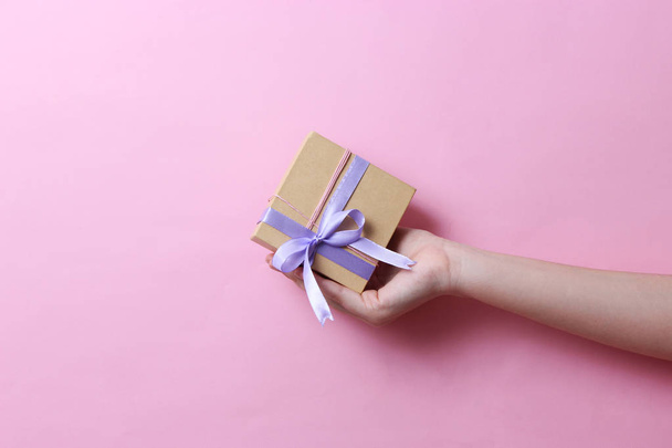 gift in female hands on a colored background. Holiday, minimalism, congratulations. - 写真・画像