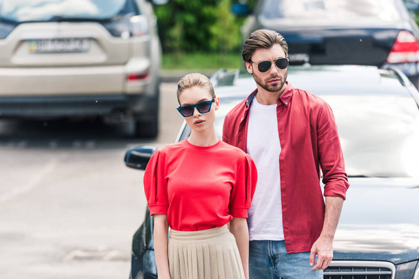 stylish young couple of models in sunglasses posing near car  - Fotoğraf, Görsel