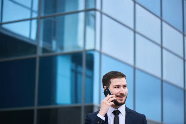 handsome bearded businessman talking on phone at street  - Фото, изображение